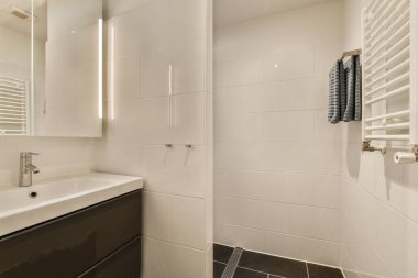 Duvarlarında siyah beyaz fayanslar olan bir banyo. Odadaki lavabo ve aynayla birlikte.