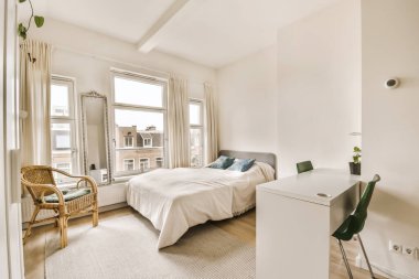 Bir yatak odası, bir sandalye ve masa şehrin caddesine bakan pencerenin önünde.