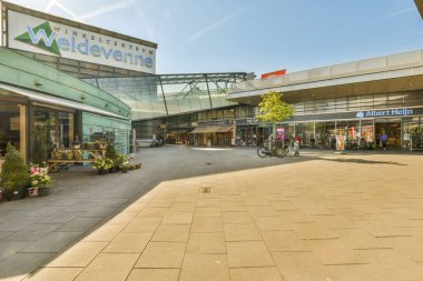 İnsanların yürüdüğü ve bisikletlerin dükkanın önündeki kaldırıma park edildiği bir alışveriş merkezinin dışında.