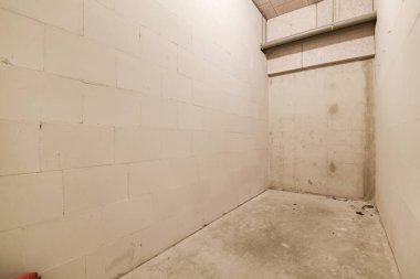 Tamamlanmamış, beyaz duvarları olan bir oda. Tuvalet veya diğer banyo malzemeleri için kullanılacak duvar da yok.