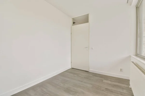 一间有木地板和白墙的空房间 有一扇通向房间左边的门 — 图库照片