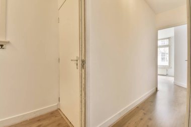 Ahşap zemini ve beyaz duvarları olan boş bir oda. Duvarda sağ tarafta büyük bir ayna var.