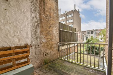 Boş bir balkon, odanın ortasında bir bank, sokağa ve binalara bakıyor.