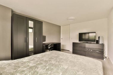 Yatağı, şifoniyeri ve yatağın önündeki duvarda televizyonu olan bir otel odası koyu ahşap.