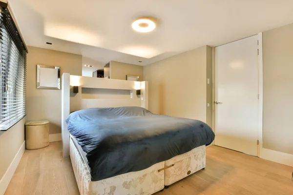 有木制地板和白色墙壁的卧室 包括用作床头板的床 — 图库照片