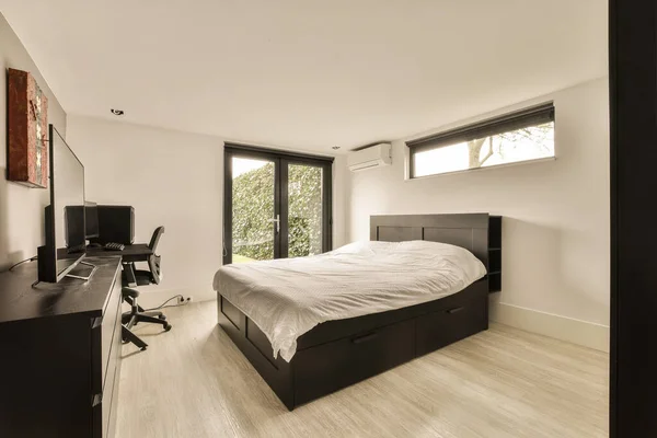 床前面的墙上有一张床 书桌和电视的卧室是白色的木地板 — 图库照片