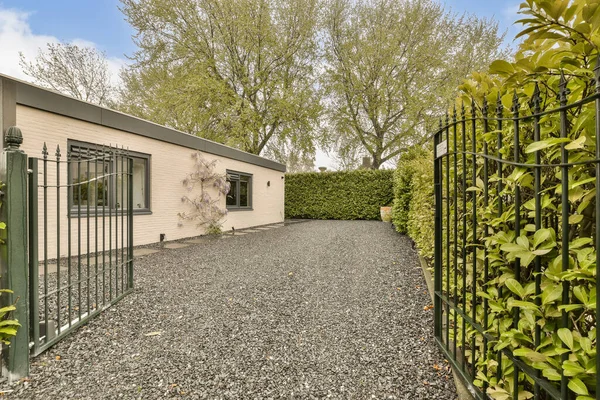 stock image a house with trees in the background and graveled driveway leading up to the front door that leads into the yard