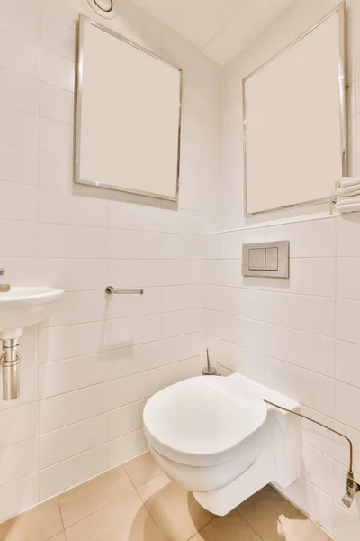 上の壁に鏡が2つあり トイレの横に沈むトイレに — ストック写真