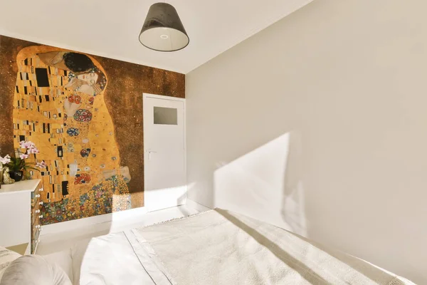 白いシートと枕のある寝室のベッドの隣の壁に描かれた女性の顔 — ストック写真