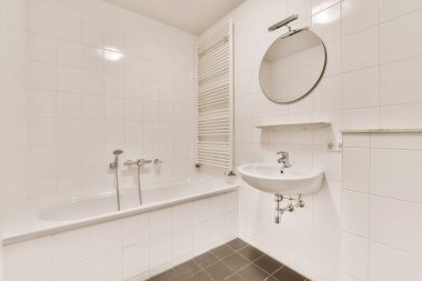 Siyah döşemeleri ve duvarları olan beyaz bir banyo lavabonun üstüne monte edilmiş bir ayna, boş bir odada.