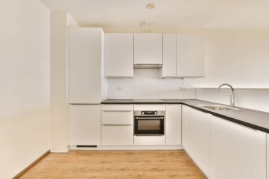 Adanın önünde beyaz dolapları ve siyah tezgahları olan bir mutfak lavabonun önünde görünmüyor, ama hiç yok.