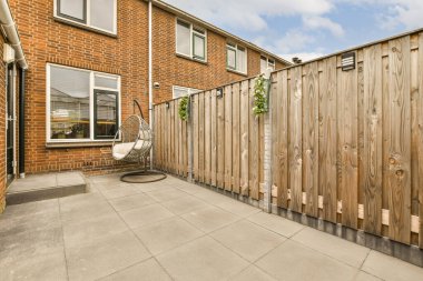 Arka planda ahşap bir çit ve tuğla bir ev olan bir dış alan, yerden göğe taşınıyor.