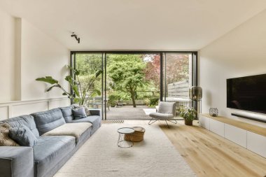 Oturma odasında kanepeler ve odanın ortasındaki duvarda düz ekran bir televizyon var.