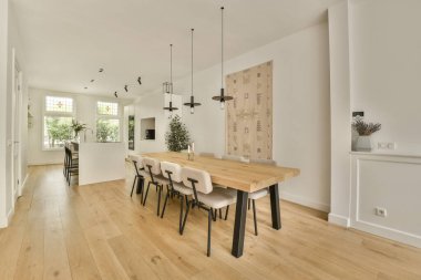 Ahşap döşemeleri ve beyaz duvarları olan bir yemek odası. Açık bir konsept ev.