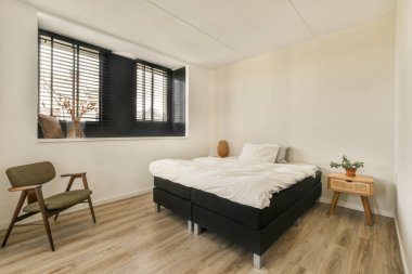 Sağ köşesinde yatak odası, sandalye ve pencere olan bir oda, birinin odasının görüntüsü.