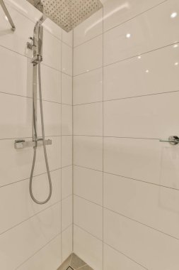 Duş başlığı ve el kamerası olan beyaz fayanslı bir banyo. Duş kabinine yerleştirilmiş.
