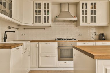 Mutfakta beyaz dolaplar ve lavabonun önünde ahşap tezgah var.