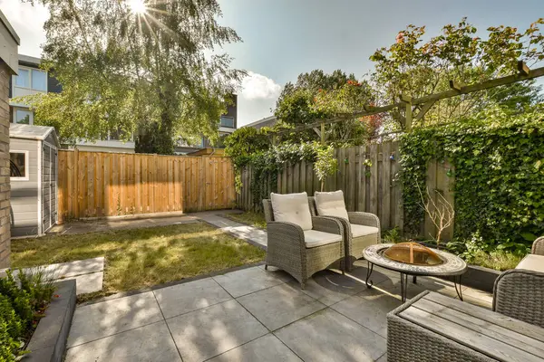 a backyard setting with furniture and trees in the back yard, as seen from the patio area on a sunny day