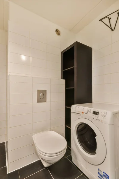 a small laundry room with a washer and dryer in the corner on the wall is white subway tiles
