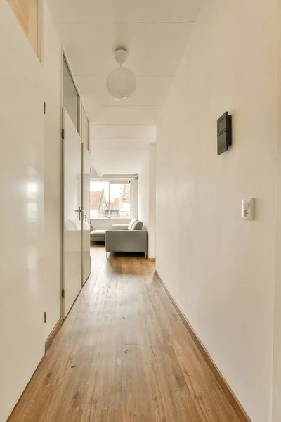 部屋の両側に木製の床と白い壁が付いている長い廊下は 角にベッドがあります — ストック写真