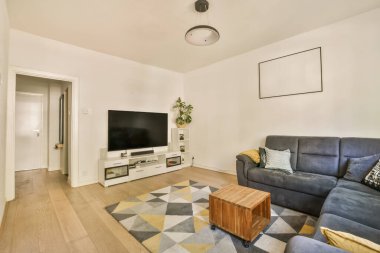 Kanepenin önündeki duvarda kanepe ve düz ekran televizyon olan bir oturma odası bir eğlence merkezi.