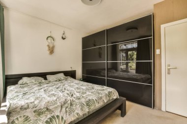 Odanın kapısının önündeki duvarda yatak odası, dolaplar ve gardırop var.