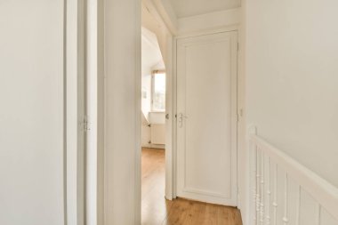 Boş bir evde beyaz duvarları ve ahşap döşemeleri olan bir koridor. Ön kapıdan girişe götürülmüş.