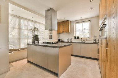 Bu odanın tezgahında ahşap dolapları ve paslanmaz aletleri olan modern bir mutfak çok hafiftir.