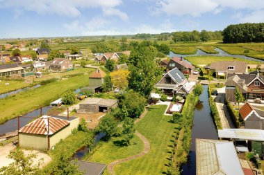 Kırsal kesimdeki bazı evlerin hava manzarası. İçlerinde su akıyor ve her iki tarafta da ağaçlar büyüyor.