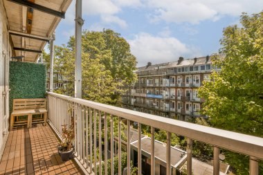 a balcony with some trees and buildings in the background on a bright sunny day, taken from an apartment balcony clipart