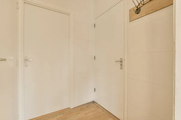 部屋の右側に白いドアと木製の床が付いている空の部屋 ドアの上に時計があります — ストック写真