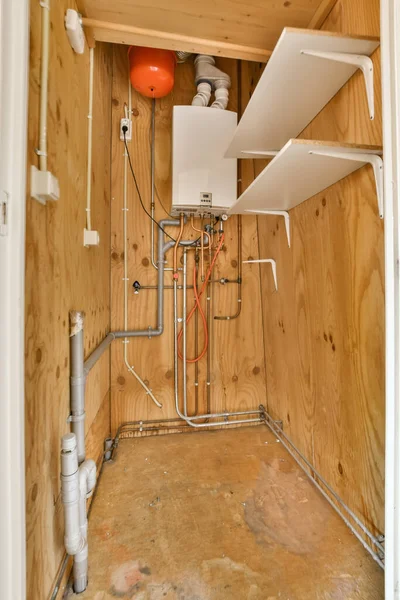 the inside of a room with pipes and water heater in its corner, which is being used for heating