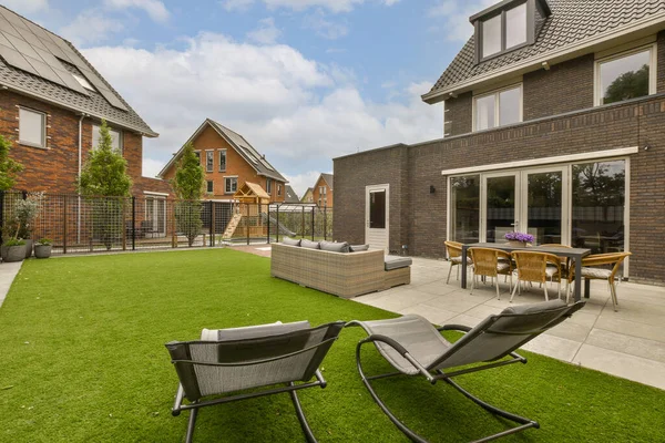 an outdoor living area with lawn and patio furniture in the middle part of the yard, surrounded by brick buildings
