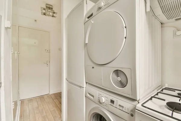 a washer and dryer in a laundry room with wood flooring, white walls and cabinets on either side