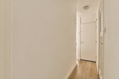 Odanın sol tarafında beyaz duvarları ve ahşap döşemeleri olan boş bir oda, sağ tarafta bir kapı var.