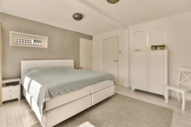 Yatak odası, şifoniyerler ve odanın önündeki duvarda beyaz dolaplar.