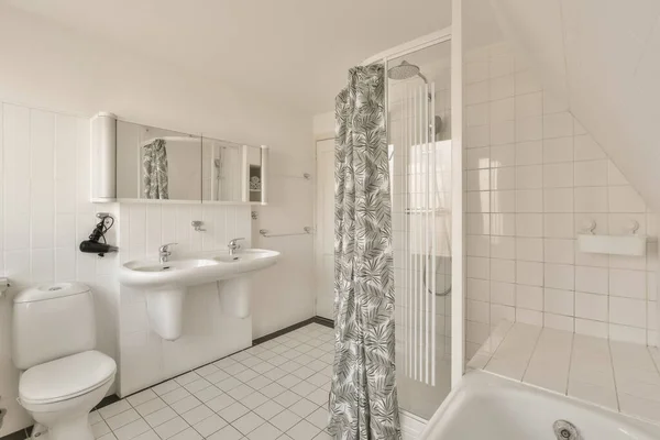 a white bathroom with black and white tiles on the floor, tub, toilet, sink and shower in it