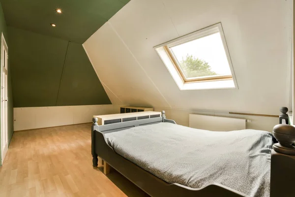 a bed in the corner of a room with green walls and white trim on the ceiling, there is a window