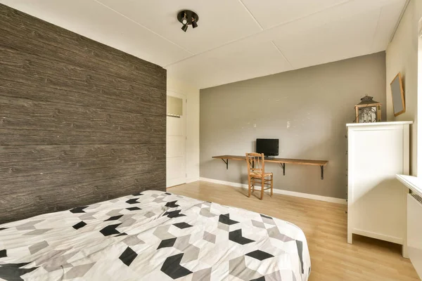 a bedroom with a bed, desk and television on the wall in front of the bed is made out of wood