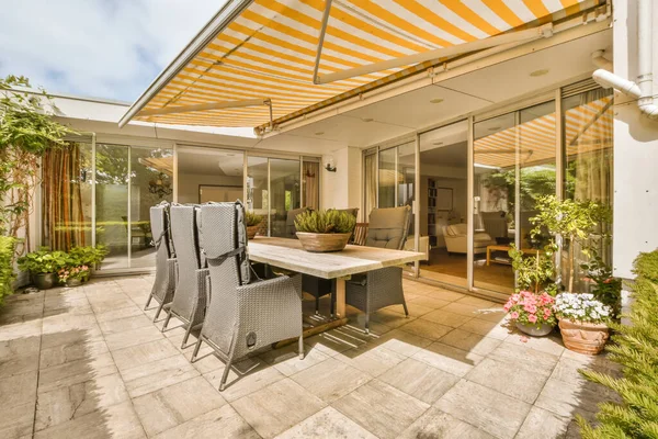 a patio with an umbrella over the dining table and chairs, in front of a large sliding glass door that opens out to a