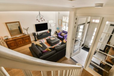 Odanın ortasında kanepeleri ve televizyonu olan bir oturma odası merdivenlerden aşağı indiriliyor.