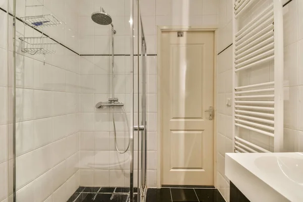 a bathroom with white tiles and black tile on the floor, along with a walk - in shower stall door