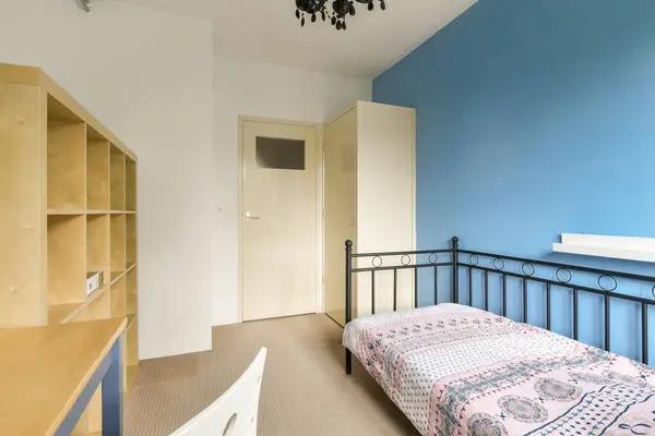 a bedroom with blue walls and white trim on the wall, there is a small bed in front of it