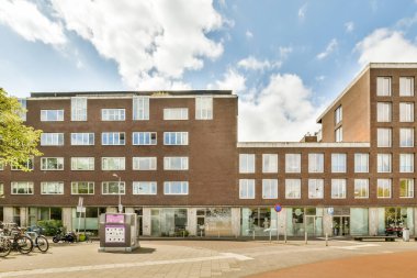 Önünde bisikletleri olan bir apartman ve caddenin karşısındaki mavi gökyüzü.