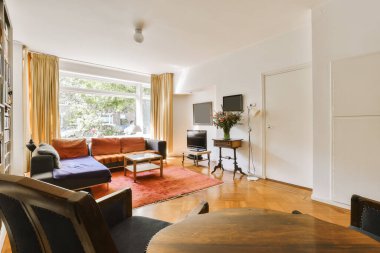 Oturma odası, koltuklar, sandalyeler ve odanın köşesindeki duvarda düz ekran televizyon.