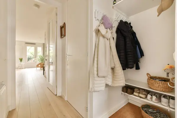 the inside of a house with wooden floors and white walls, there is a coat rack hanging on the wall