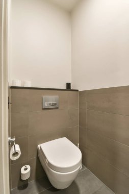 Banyonun köşesinde yerde ve duvarlarda fayans olan bir tuvalet, tamamen beyaz.