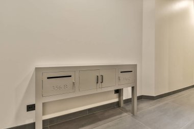 Duvarında posta kutuları olan boş bir oda ve ortasında iki kapı olan bir kapı açıkken diğerinin kapısı açık.