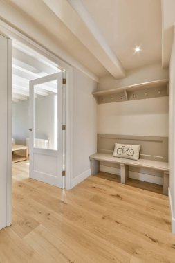 Duvarlarında, pencerelerinde ve kapılarında ahşap döşeme ve beyaz süslemeler olan bir evin içinde.