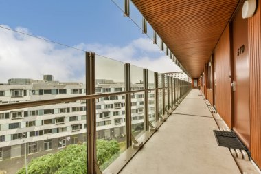 Arka planda bazı binalar ve üzerinde mavi bir gökyüzü olan bir balkon, bir apartman balkonundan görüldüğü gibi.